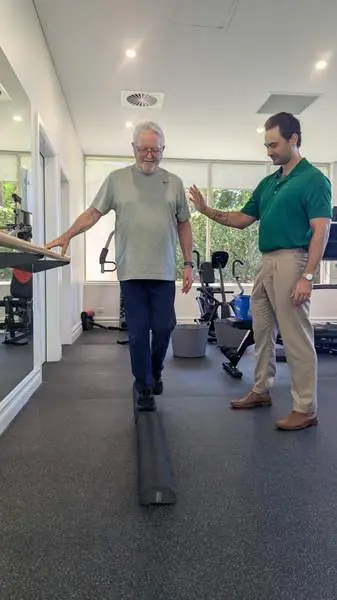 A physiotherapist guiding an older man through a balance exercise